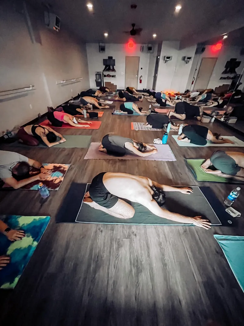 Students in child's pose during a hot yoga class